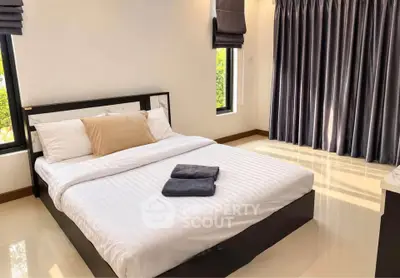 Spacious bedroom with modern decor and large windows for natural light.