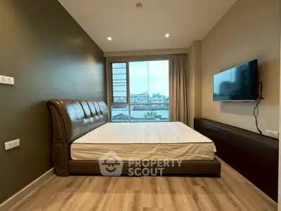 Modern bedroom with large window and city view, featuring a sleek wall-mounted TV and stylish leather bed.