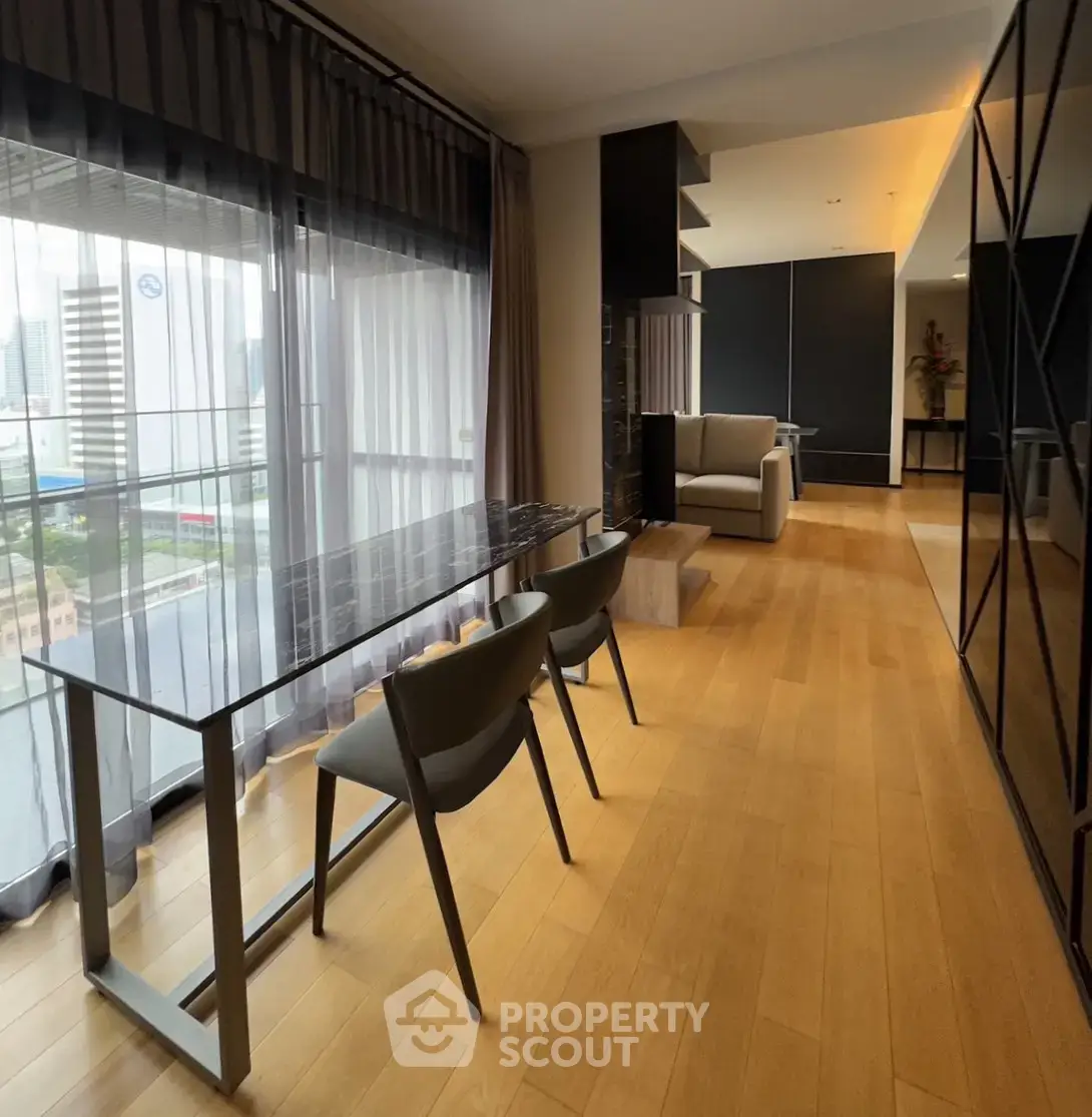 Modern living room with city view, featuring sleek furniture and floor-to-ceiling windows.