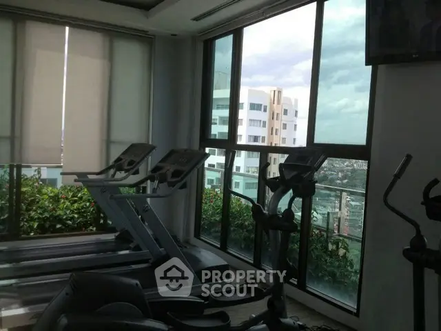 Modern gym with treadmills and large windows offering city views.