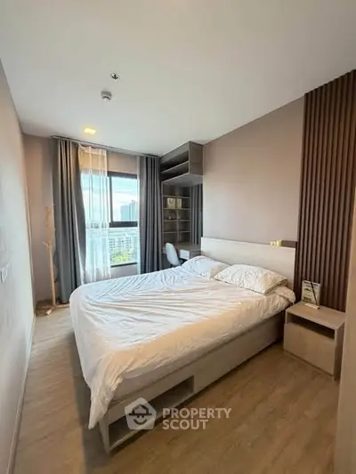 Modern bedroom with large window and stylish decor in a high-rise apartment.