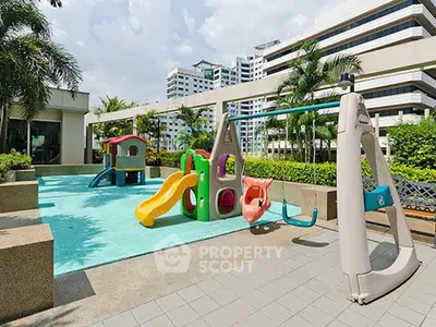Modern apartment complex with children's playground and lush greenery.