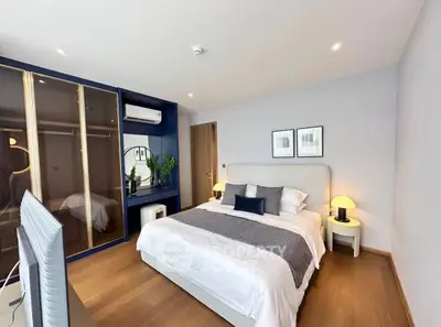 Modern bedroom with stylish decor, featuring a cozy bed, wooden flooring, and a sleek wardrobe.