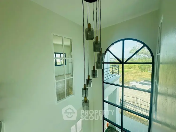 Stunning modern home with high ceilings and large arched window offering scenic views.
