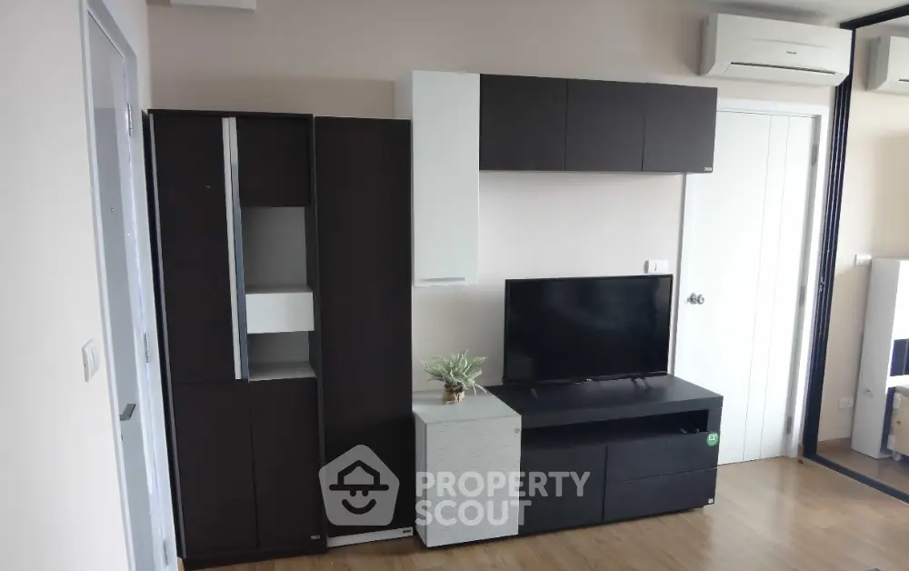 Modern living room with sleek furniture and wall-mounted TV, featuring air conditioning and stylish decor.