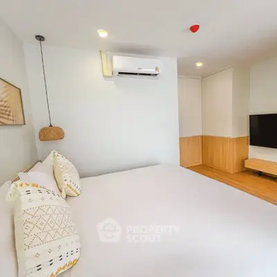Modern bedroom with minimalist design, featuring a cozy bed, wall-mounted TV, and air conditioning.