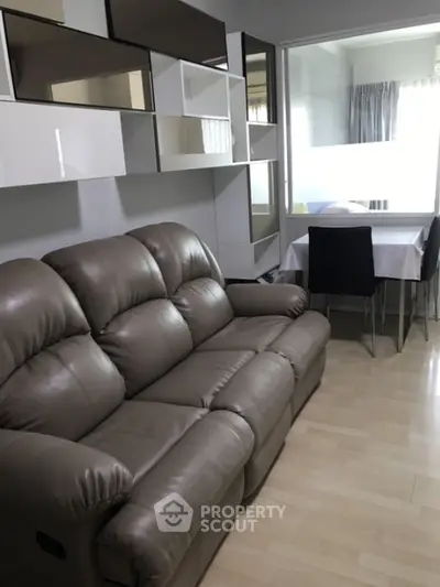 Modern living room with leather sofa and dining area in compact apartment