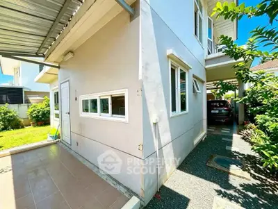 Modern two-story house with carport and lush garden, perfect for family living.