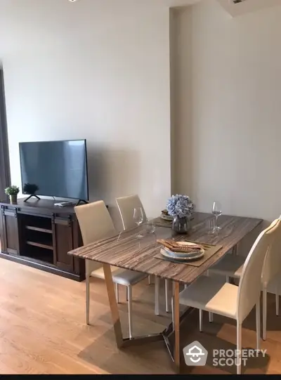 Modern dining area with sleek table and chairs, adjacent to a stylish TV stand in a bright living space.