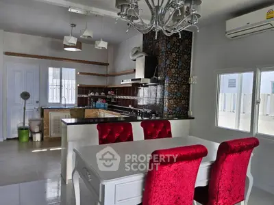 Elegant kitchen with red velvet chairs and modern chandelier in a stylish open layout.