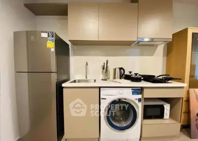 Modern kitchen with appliances including fridge, washing machine, and microwave in compact layout.