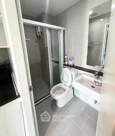 Modern bathroom with sleek design, featuring a shower, toilet, and sink in a compact layout.