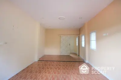 Spacious and well-lit empty living space with terracotta tiled flooring and neutral wall colors, ready for personalization.