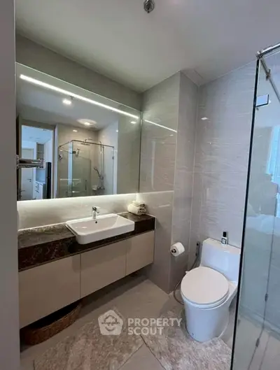 Modern bathroom with sleek design, featuring a glass shower and elegant vanity.