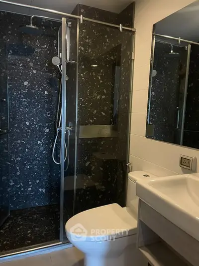 Modern bathroom with sleek black stone shower and white fixtures