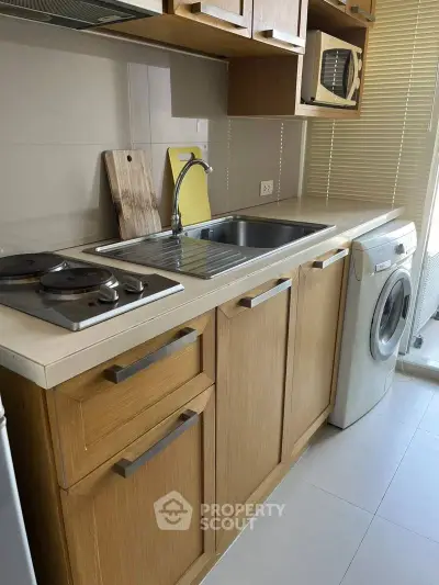 Modern kitchen with wooden cabinets, washing machine, and electric stove in compact layout.