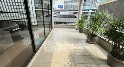 Spacious balcony with city view and lush potted plants, perfect for relaxation.