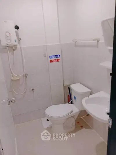 Compact bathroom with shower, toilet, and sink in a modern apartment.