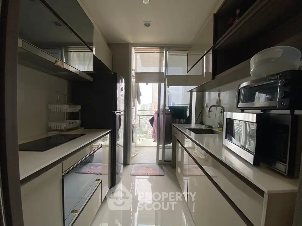 Modern kitchen with sleek appliances and open layout leading to a balcony view.