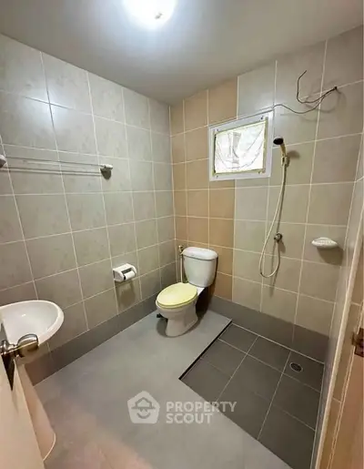Spacious bathroom with modern fixtures and tiled walls, featuring a shower and toilet.