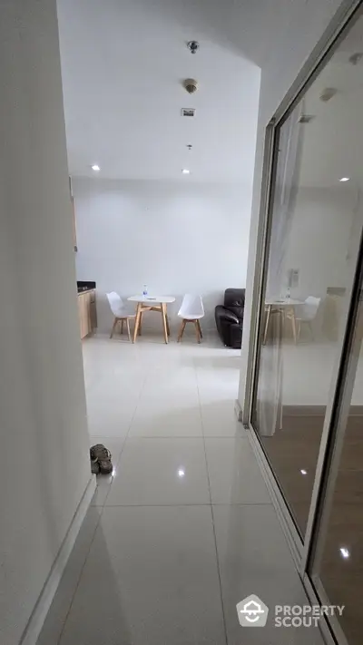 Modern apartment hallway leading to a cozy dining area with stylish chairs and table.