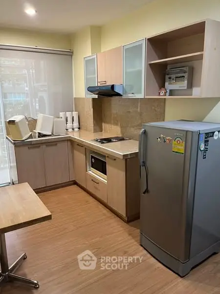 Modern kitchen with sleek cabinets, stainless steel fridge, and built-in oven in cozy apartment.