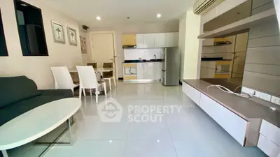 Modern open-plan living room with sleek kitchen and dining area, featuring contemporary furniture and bright lighting.
