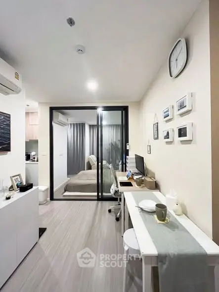 Modern studio apartment with sleek design and cozy bedroom separated by glass partition.