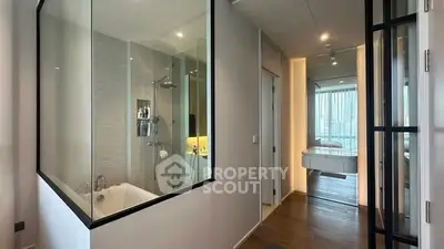 Modern apartment with glass-walled bathroom and sleek hallway design