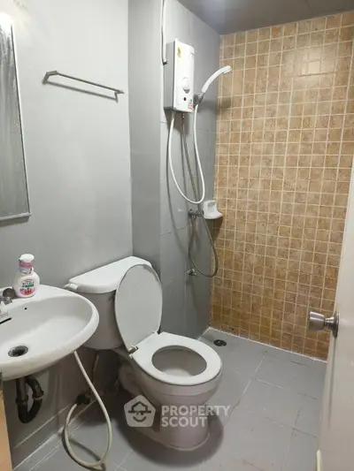Compact bathroom with shower, toilet, and sink in neutral tones.