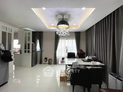 Spacious modern living room with elegant chandelier and floor-to-ceiling curtains