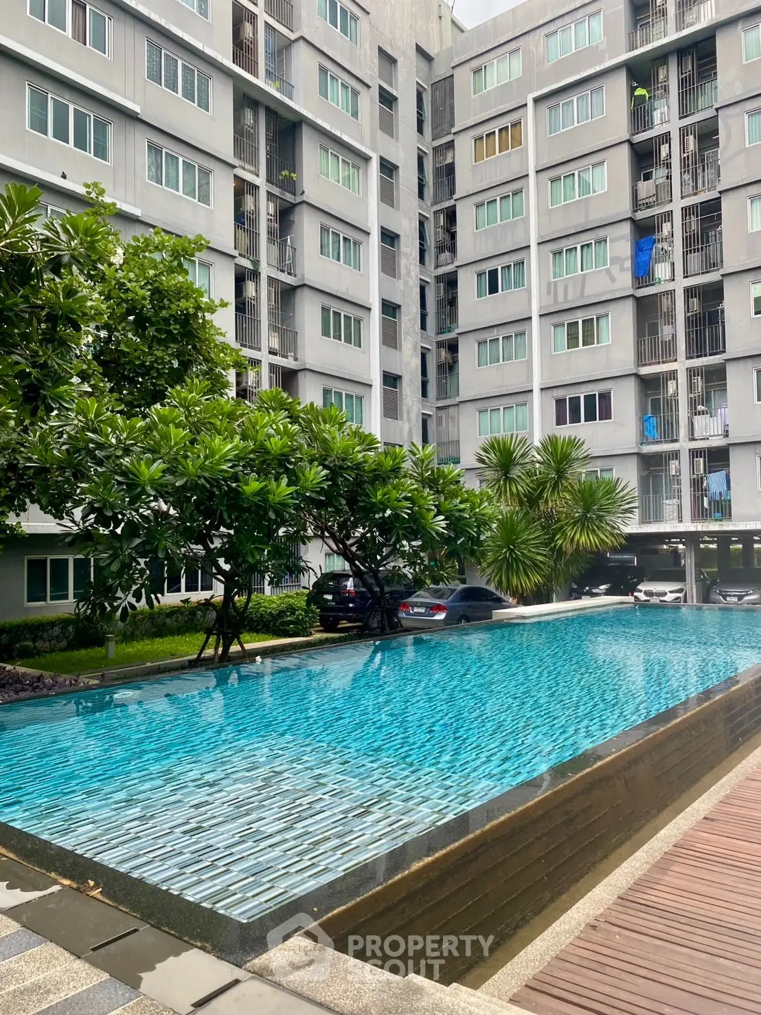 Modern apartment building with a serene swimming pool and lush greenery.