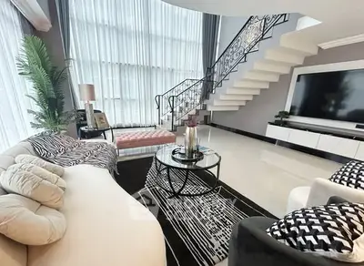 Luxurious modern living room with elegant staircase and large TV, perfect for stylish entertaining.