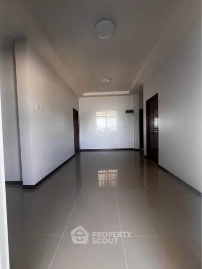 Spacious empty room with glossy tiled floor and modern lighting, perfect for customization.