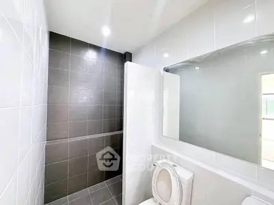 Modern bathroom with sleek tiles and large mirror, featuring a clean and minimalist design.