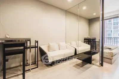 Modern living room with sleek furniture and mirrored wall in a stylish apartment.
