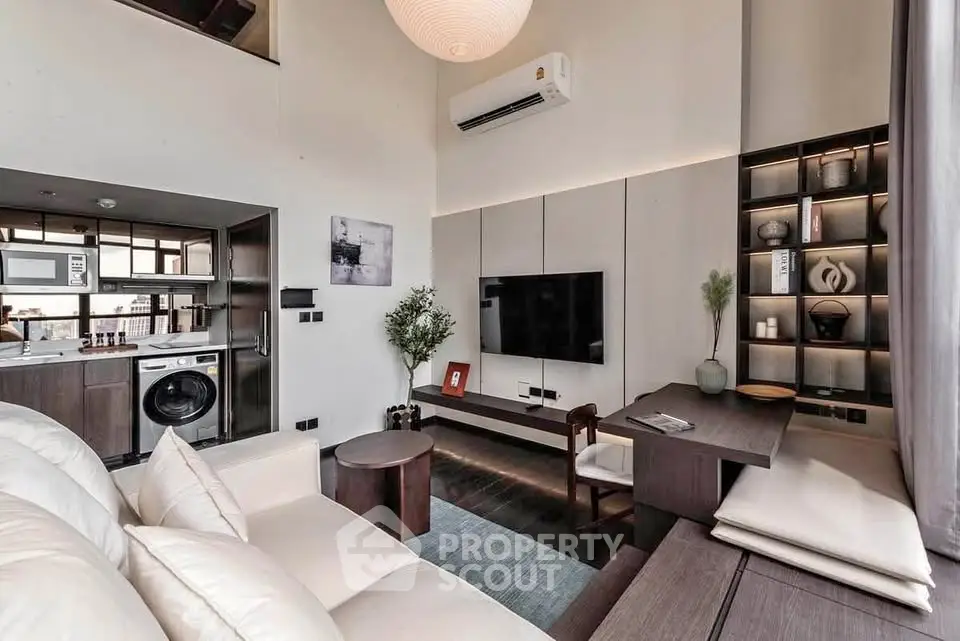 Modern living room with sleek design, featuring built-in shelves, cozy seating, and integrated kitchen appliances.