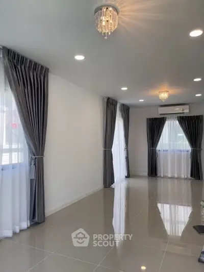 Spacious living room with elegant curtains and modern lighting in a bright, airy apartment.