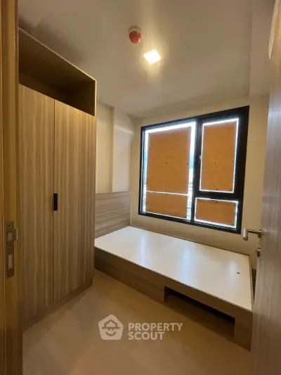 Modern bedroom with built-in wardrobe and large window, perfect for urban living.
