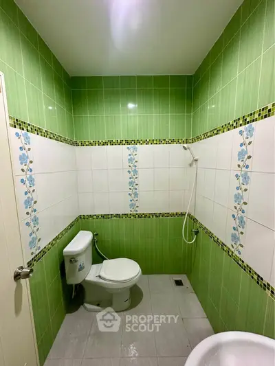 Bright green-tiled bathroom with floral accents and modern fixtures.