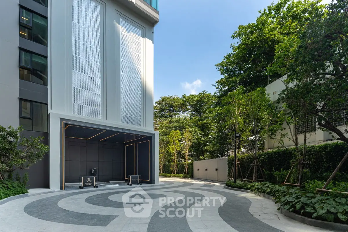 Modern building entrance with stylish circular driveway and lush greenery