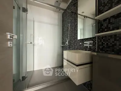 Modern bathroom with sleek glass shower and stylish mosaic tiles