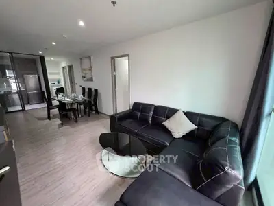 Spacious modern living room with sleek black sectional sofa and elegant dining area.