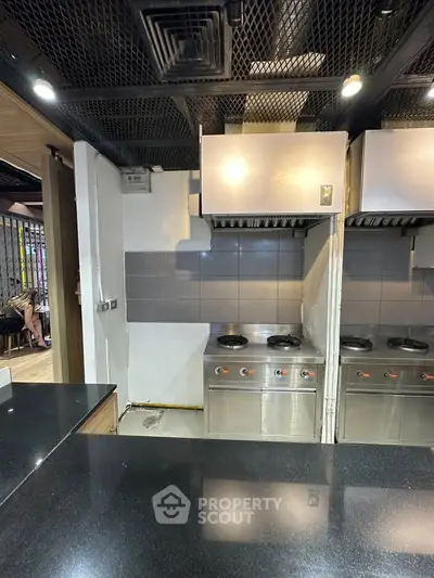 Commercial kitchen with stainless steel appliances and black countertop, ideal for restaurant setup.