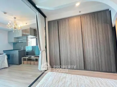 Modern studio apartment with open layout, featuring a sleek kitchen and elegant chandelier lighting.