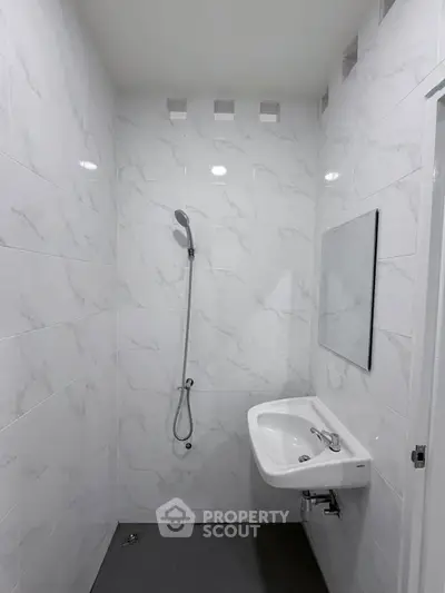 Modern minimalist bathroom with sleek white tiles and wall-mounted sink.