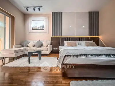Luxurious bedroom with elegant decor and cozy seating area, featuring hardwood floors and modern lighting.