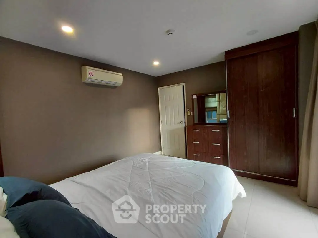 Cozy bedroom with air conditioning and wooden wardrobe