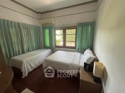 Cozy bedroom with twin beds and natural light, perfect for relaxation.