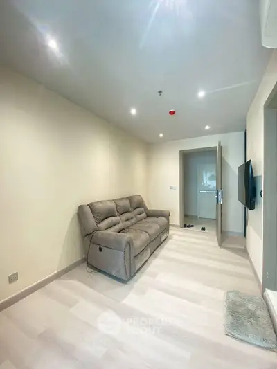 Modern living room with plush sofa and wall-mounted TV in a cozy apartment.